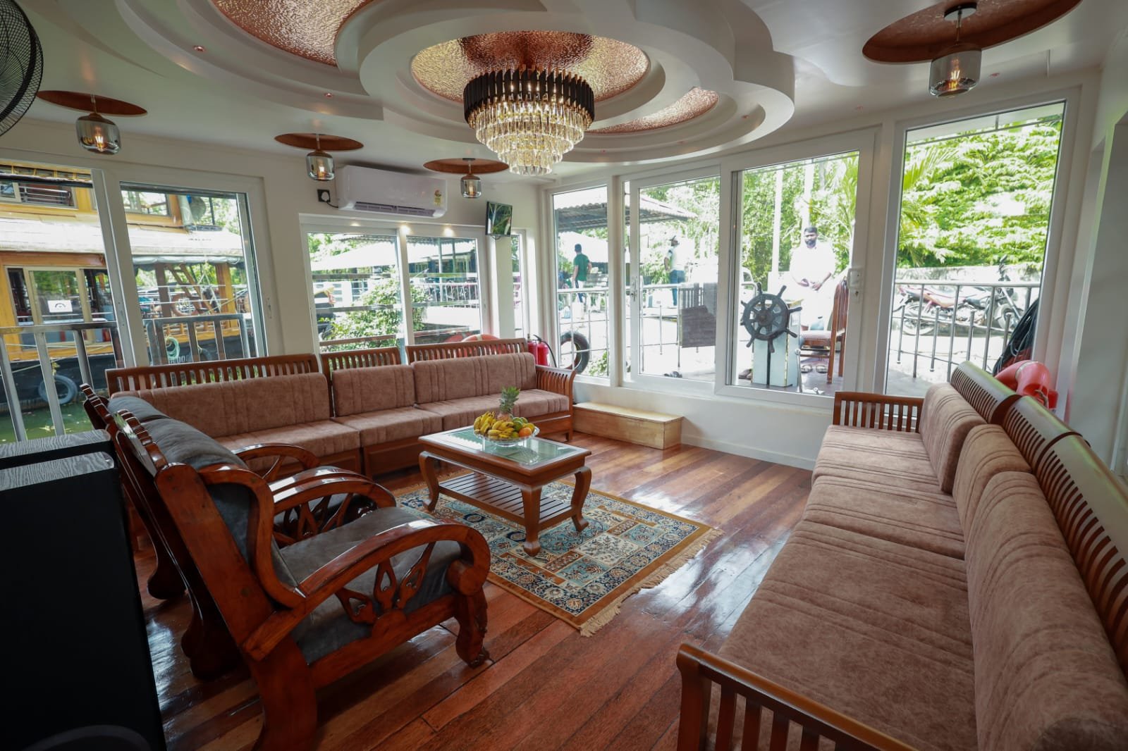 Luxurious indoor lounge with plush seating and panoramic windows aboard our 5 bedroom houseboat Alleppey.
