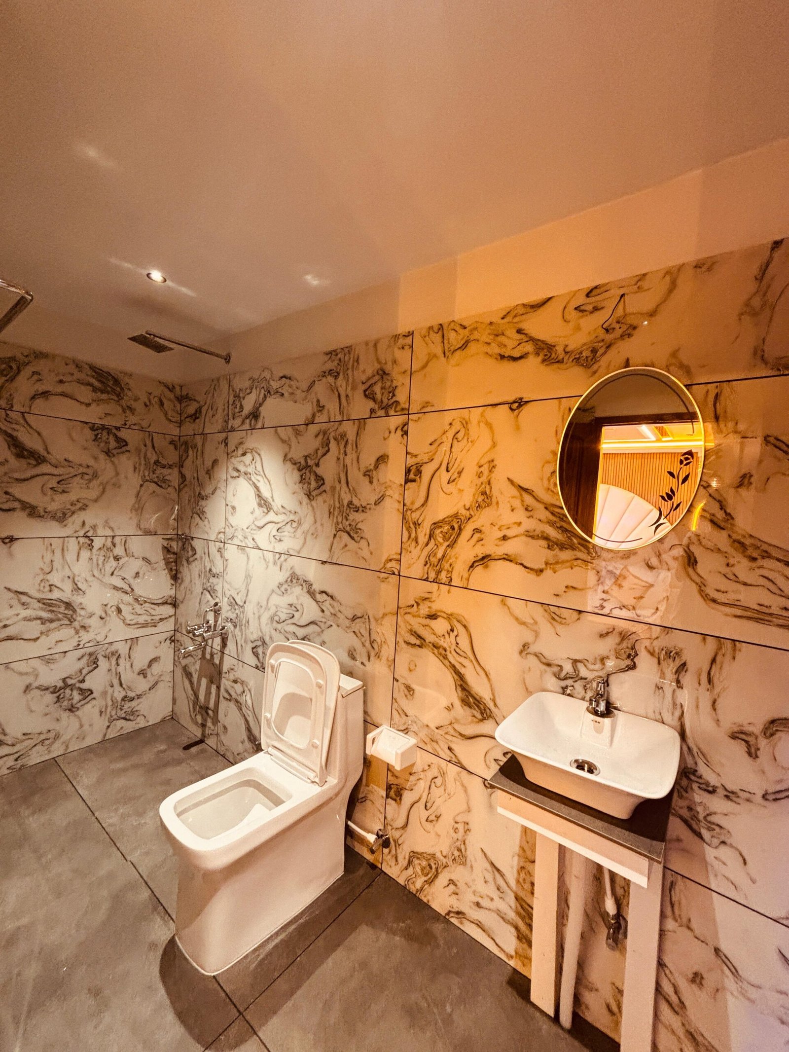 Modern Attached Bathroom Clean and modern attached bathroom featuring elegant marble tiles, a western toilet, and an illuminated mirror inside a premium twin-room boat stay.
