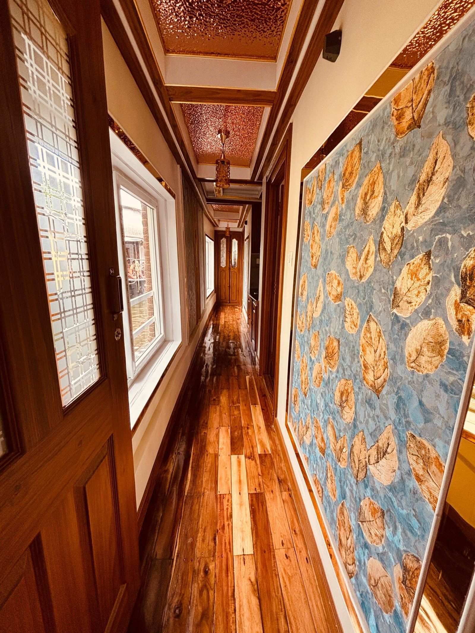 Interior Corridor - Houseboat Alleppey Elegant wooden hallway with decorative leaf wall art connecting the rooms inside our 2 bedroom houseboat in Alleppey.
