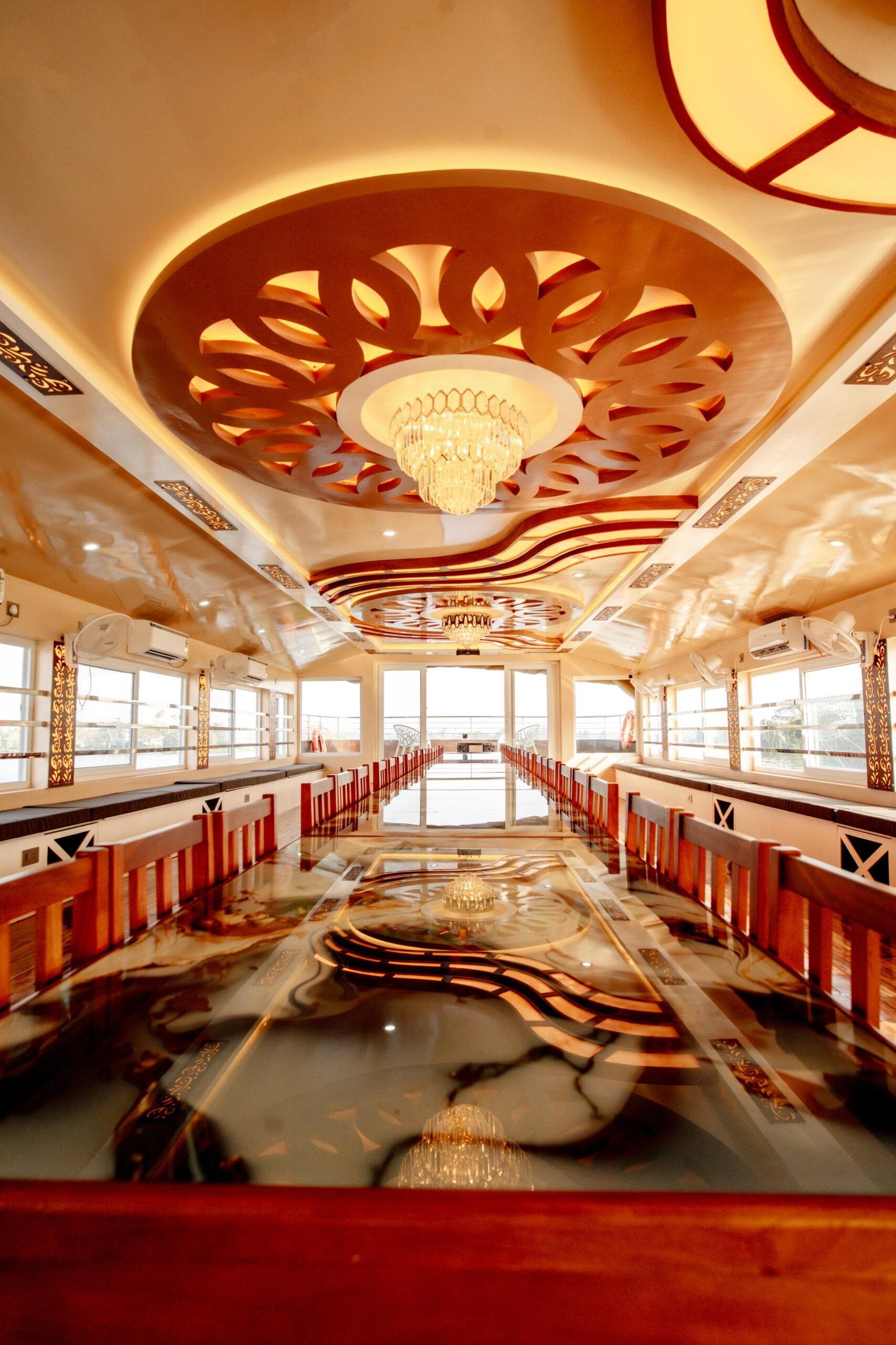 Long banquet seating with panoramic glass windows offering backwater views during your Alleppey cruise