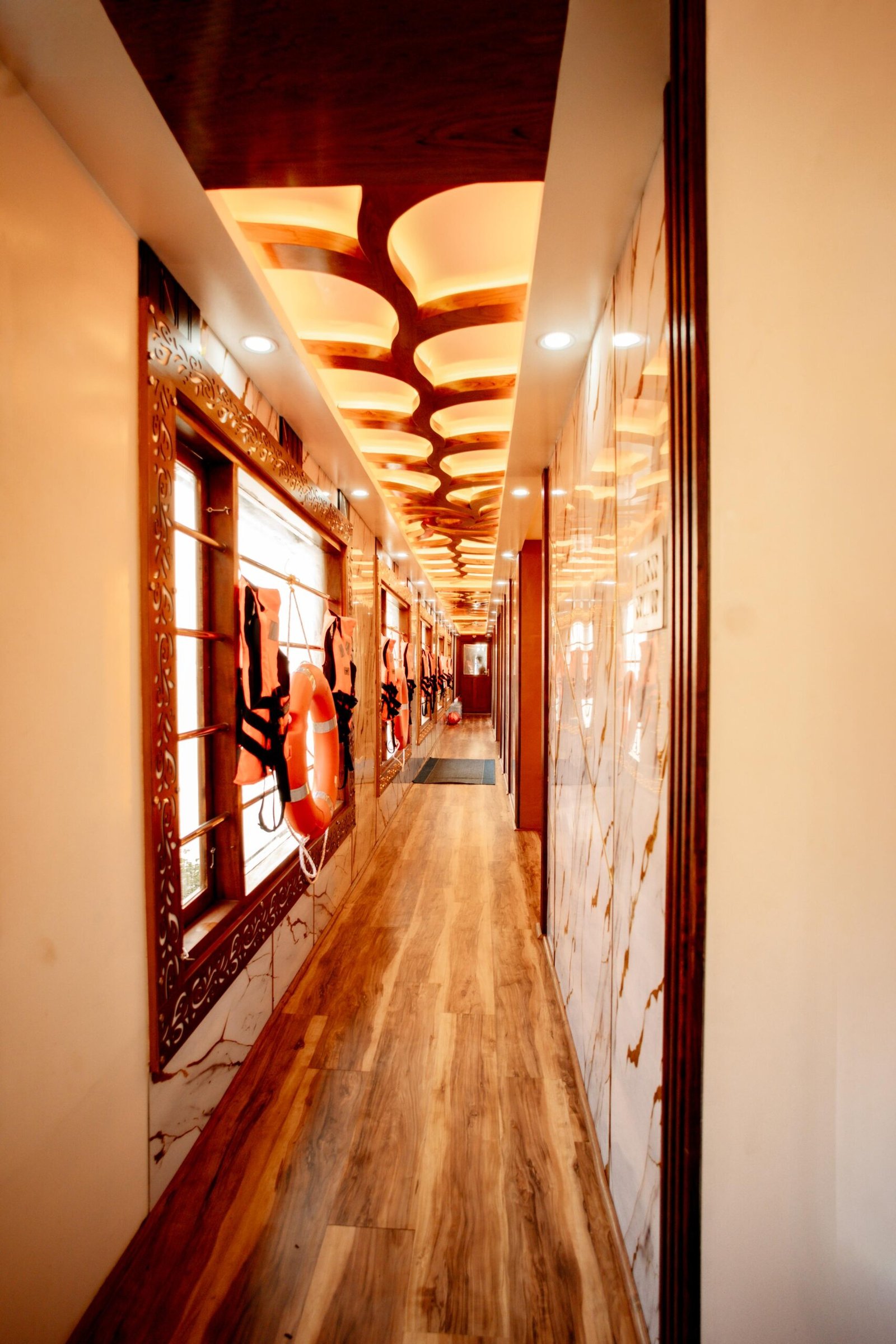 Long wooden corridor equipped with safety life jackets aboard our 7 bedroom houseboat Alleppey