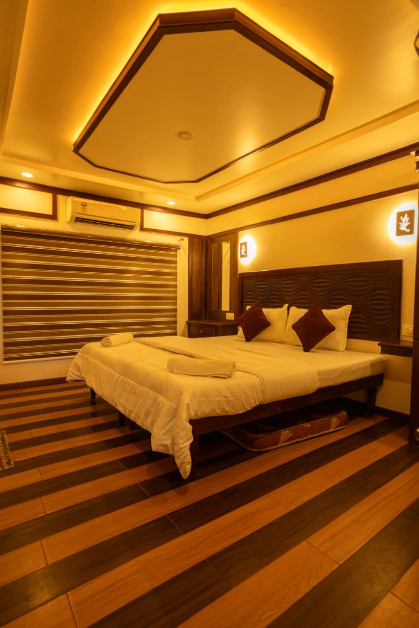 Guest AC Bedroom - 6 Bedroom Houseboat Alleppey Comfortable air-conditioned guest bedroom featuring traditional wooden decor and warm lighting on a 6 bedroom houseboat alleppey.