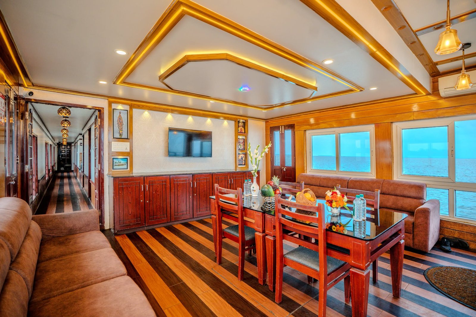 Elegant Dining Setup - 6 Bedroom Houseboat Alleppey Elegant dining table setup with a fresh fruit basket inside the spacious lounge of our premium 6 bedroom houseboat Alleppey.