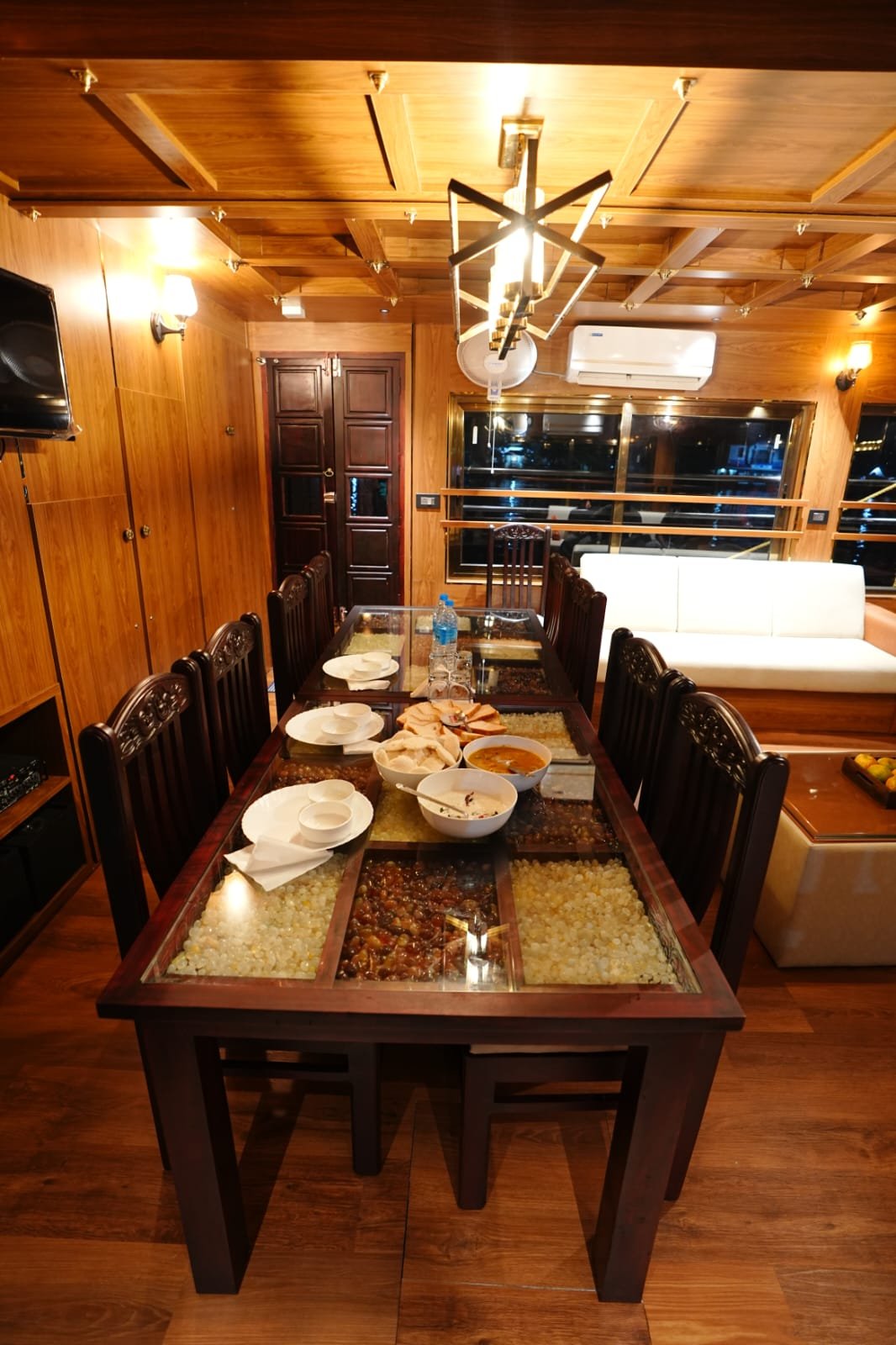 Spacious air-conditioned indoor lounge and glass dining table inside a luxury four-room boat stay.