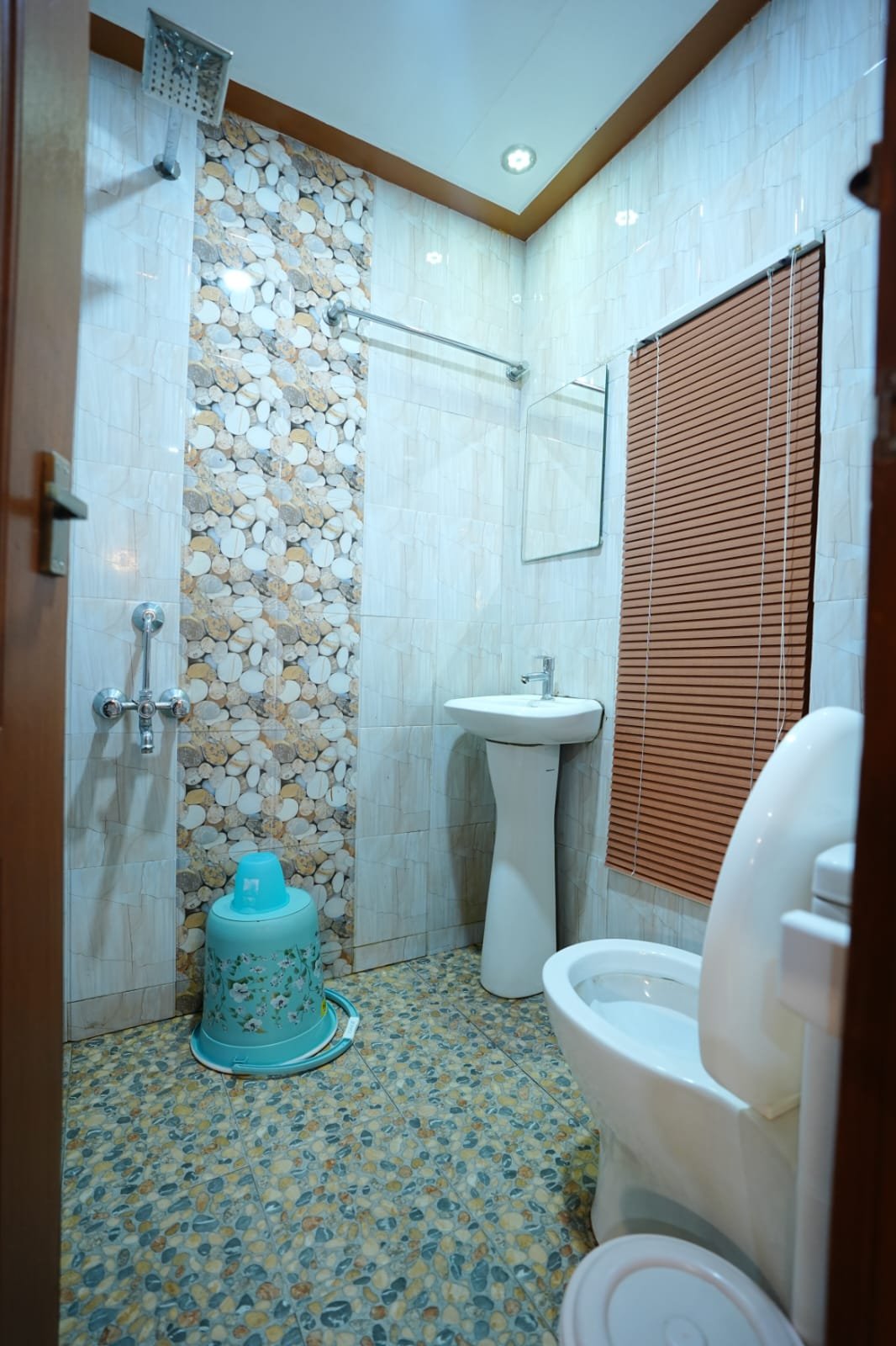 Clean and hygienic attached bathroom with a shower and western toilet inside a four-room boat stay.