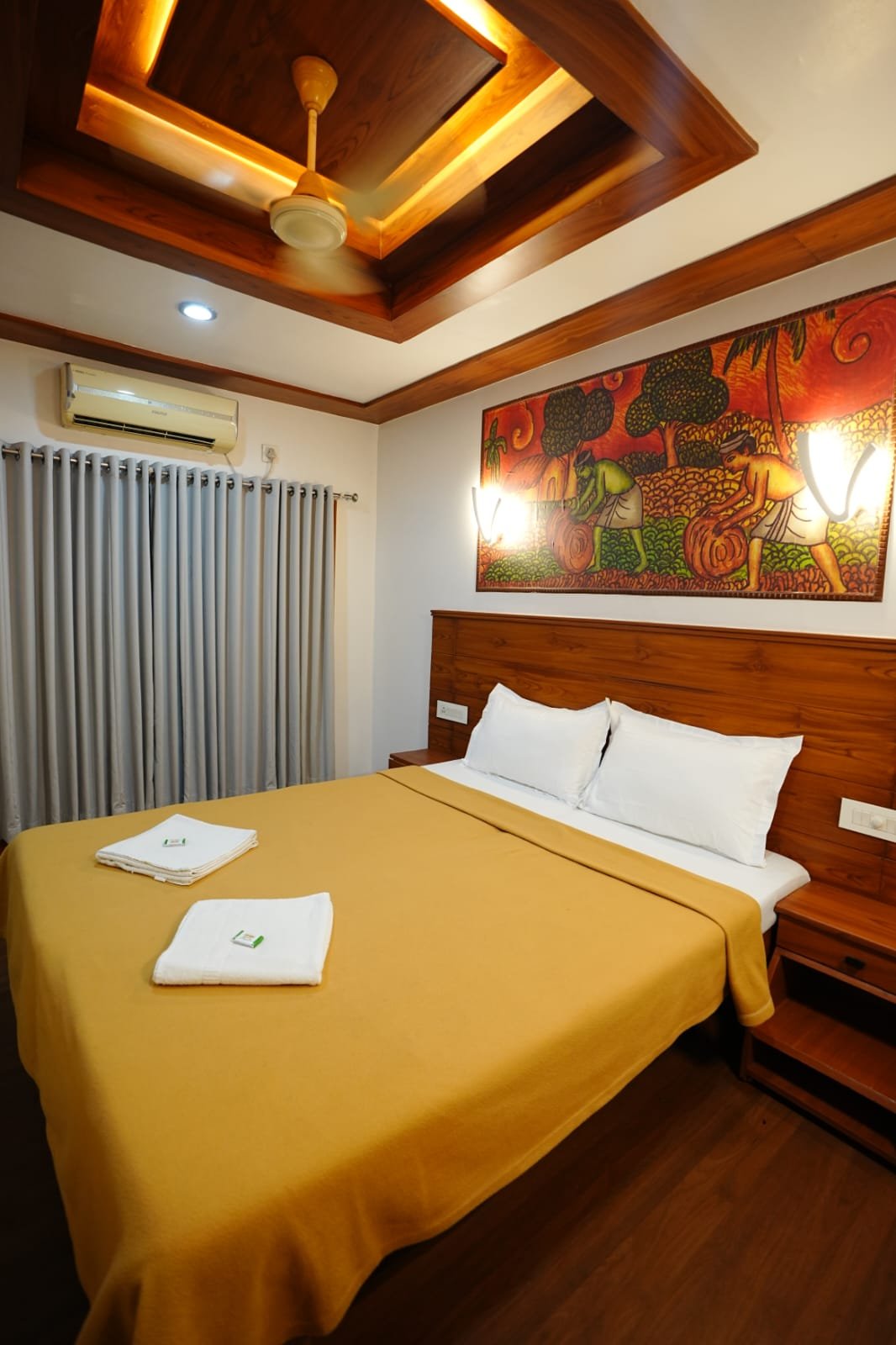 Bright and comfortable AC bedroom featuring traditional Kerala wall art on a private backwater cruise.