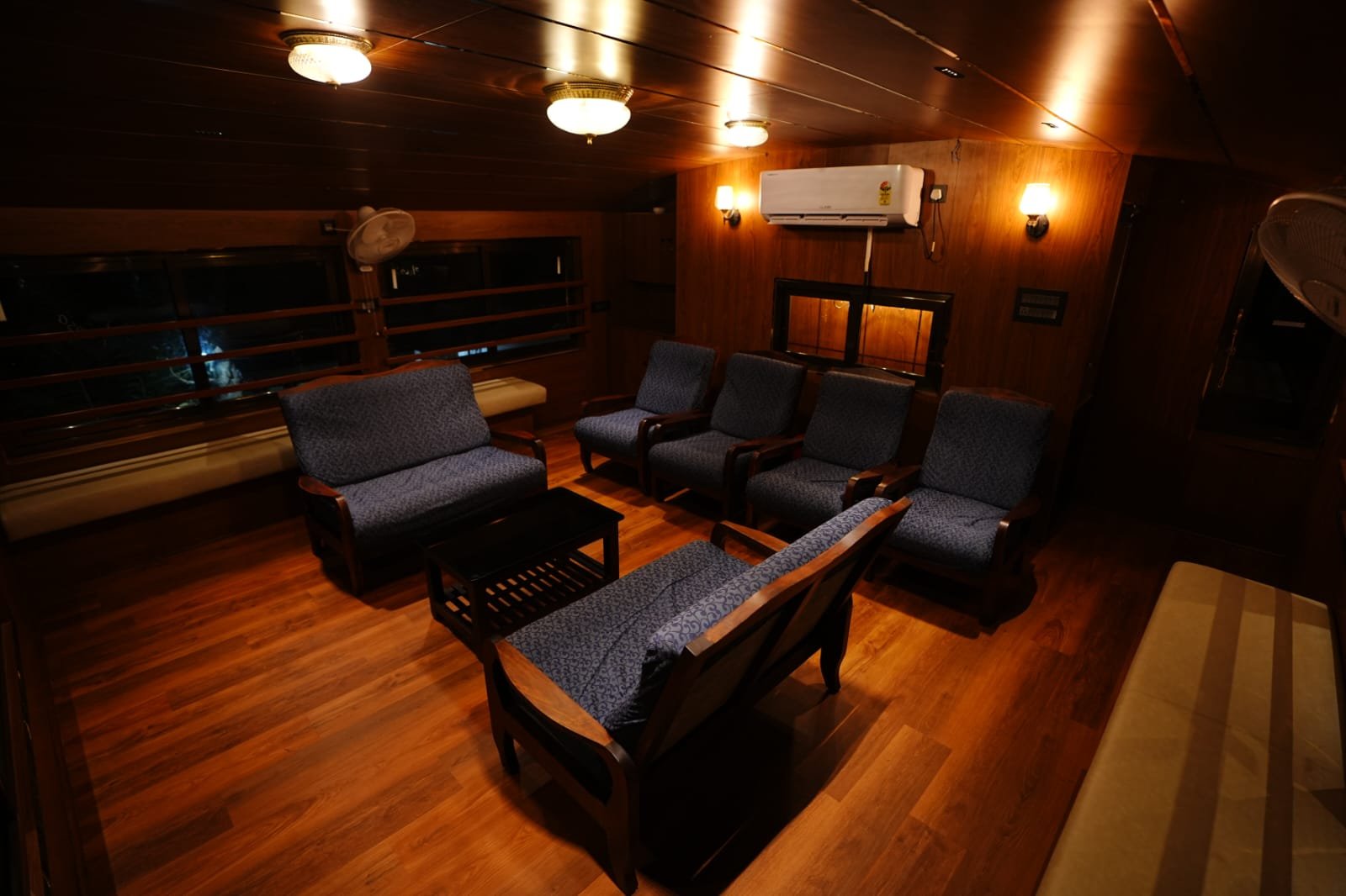 Cozy indoor lounge area with blue seating inside a 4 bedroom houseboat Alleppey.