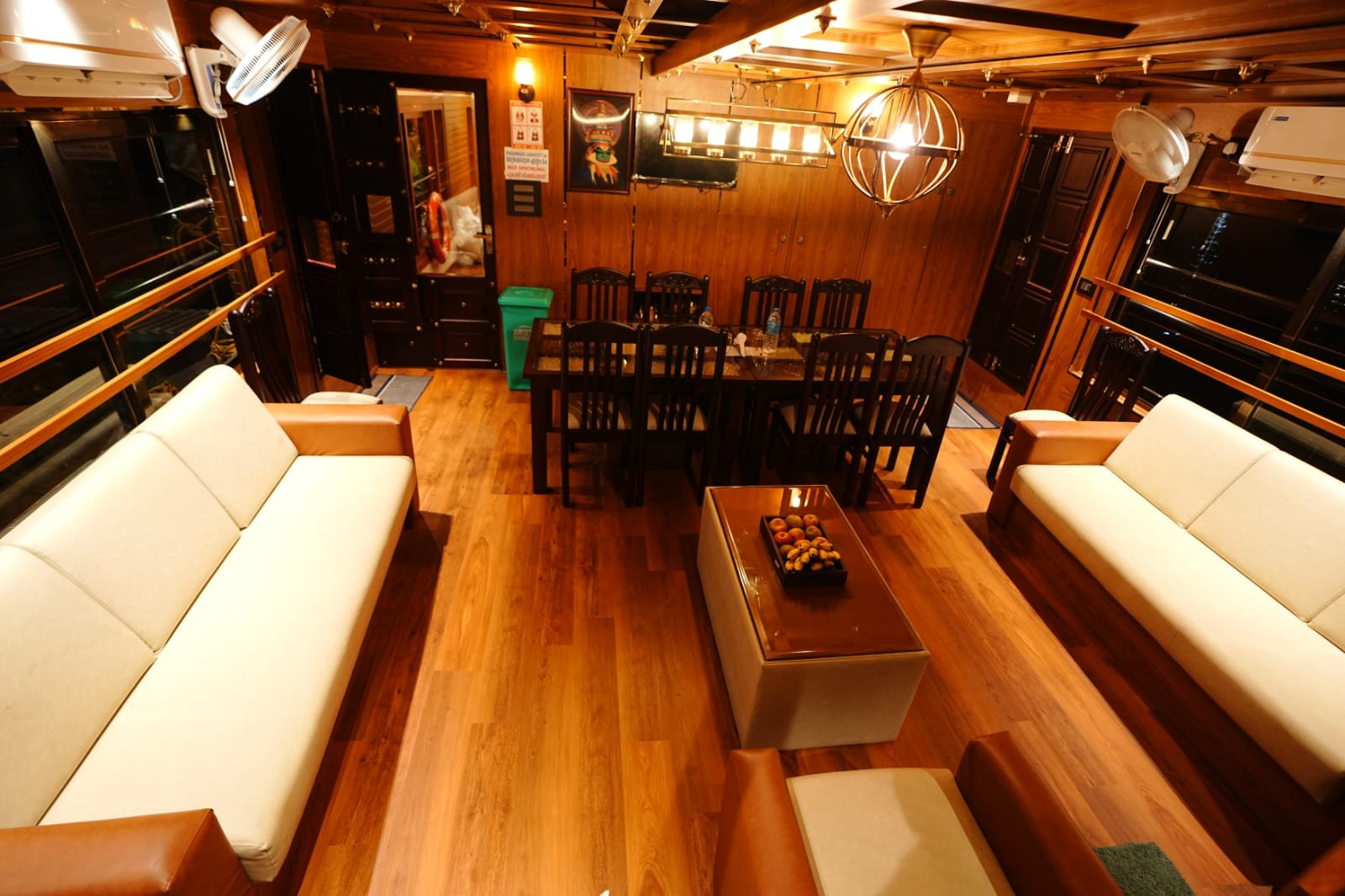 Comfortable wooden living space featuring plush white seating inside our private Kerala houseboat.
