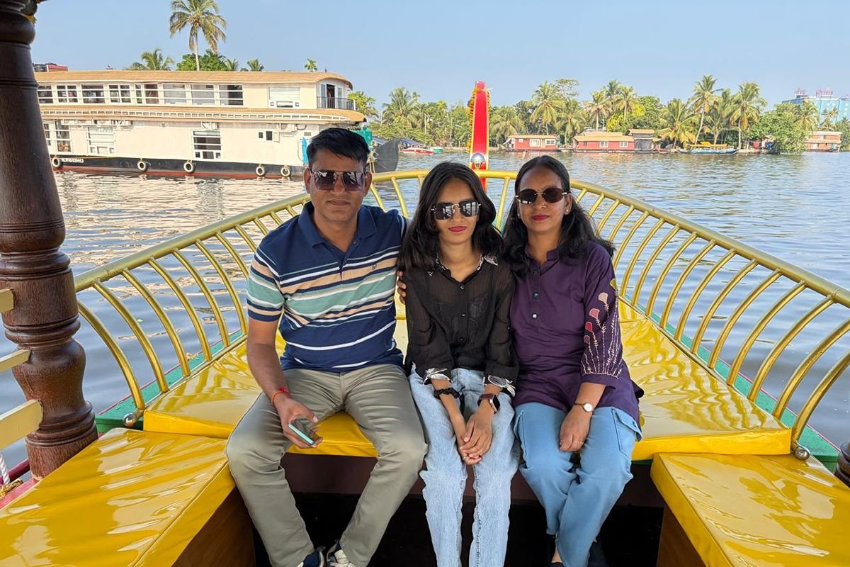 A family of three posing on the yellow deck of a boat while enjoying a relaxing shikara ride in Alleppey backwaters.